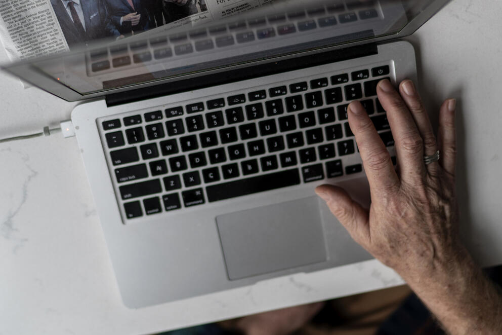 A right hand is on a laptop keyboard.