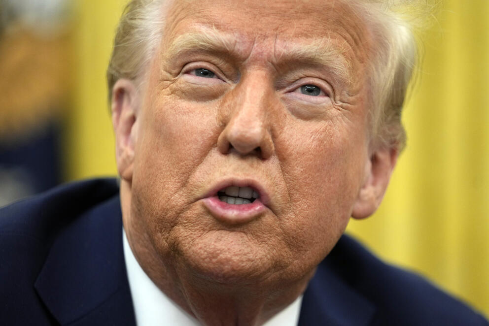 A close up of President Trump speaking with a yellow background