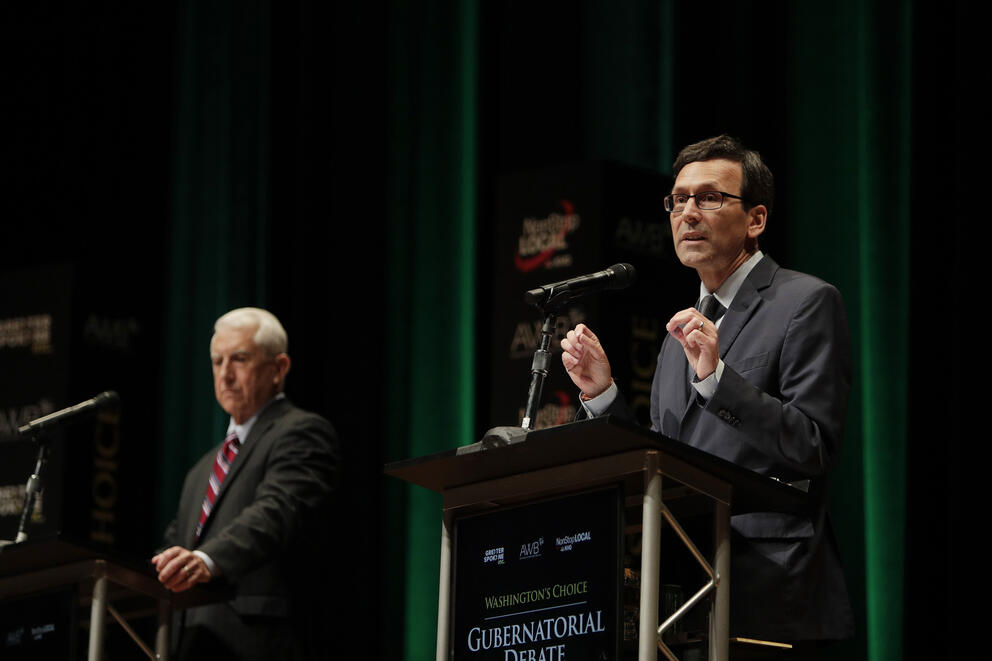 On the left, Dave Reichert stands behind a podium next to Bob Ferguson, left, at a Washington Debate Coalition debate