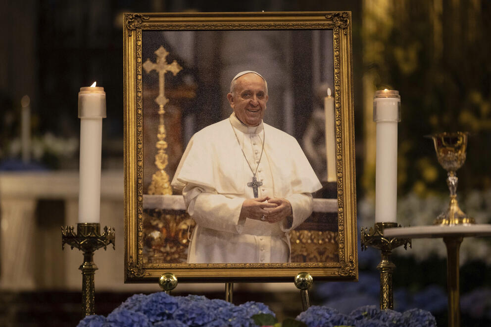 A picture of Pope Francis in white vestments is displayed between two candles at St. Patrick's Cathedral in New York.