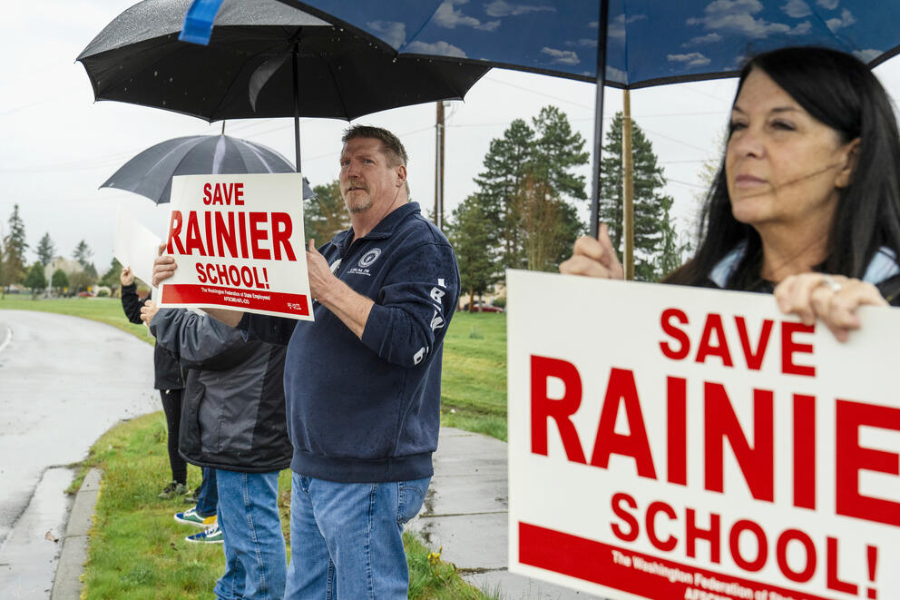 Protesters hold signs that say "Save Rainier School"