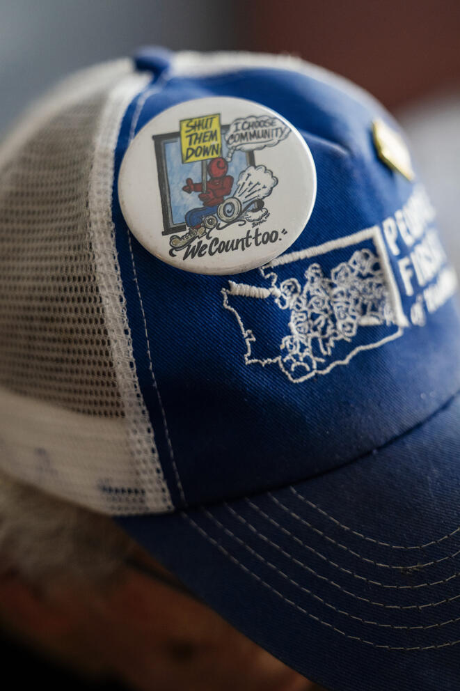 A baseball hat with a pin that says "Shut them down" 