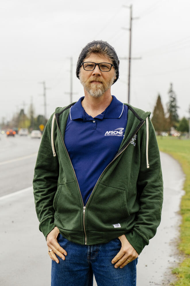 A man poses for a portrait on the side of a street