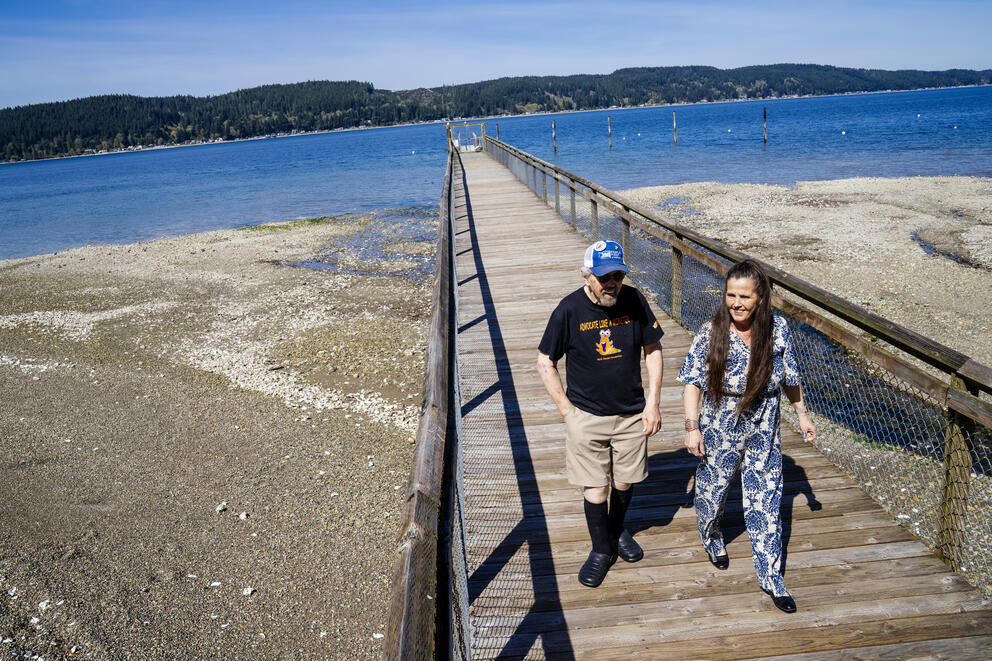 A man and a woman walk on a pier.