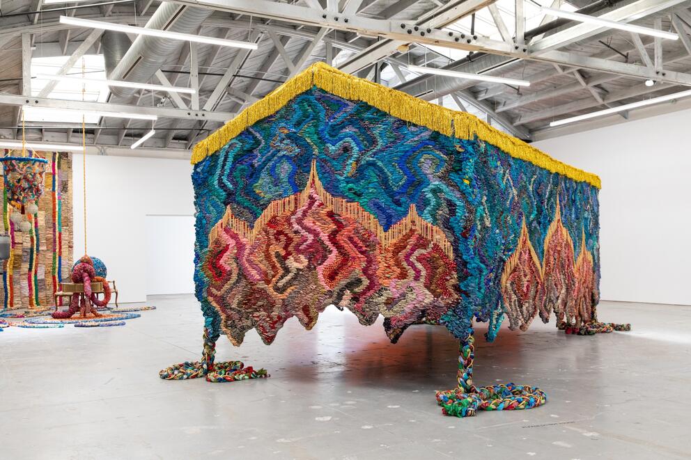photo of a gallery installation of a colorful textile structure made from woven saris