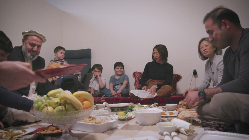 People sit on the floor around a spread of food.