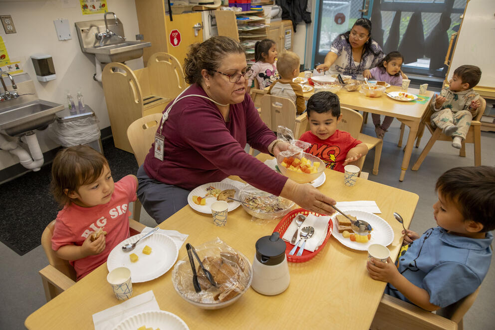 A teacher feeds students during lunch.