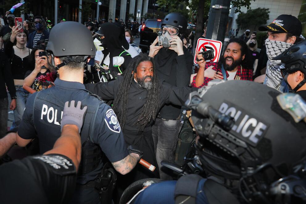 two police officers move in on a crowd of protesters 