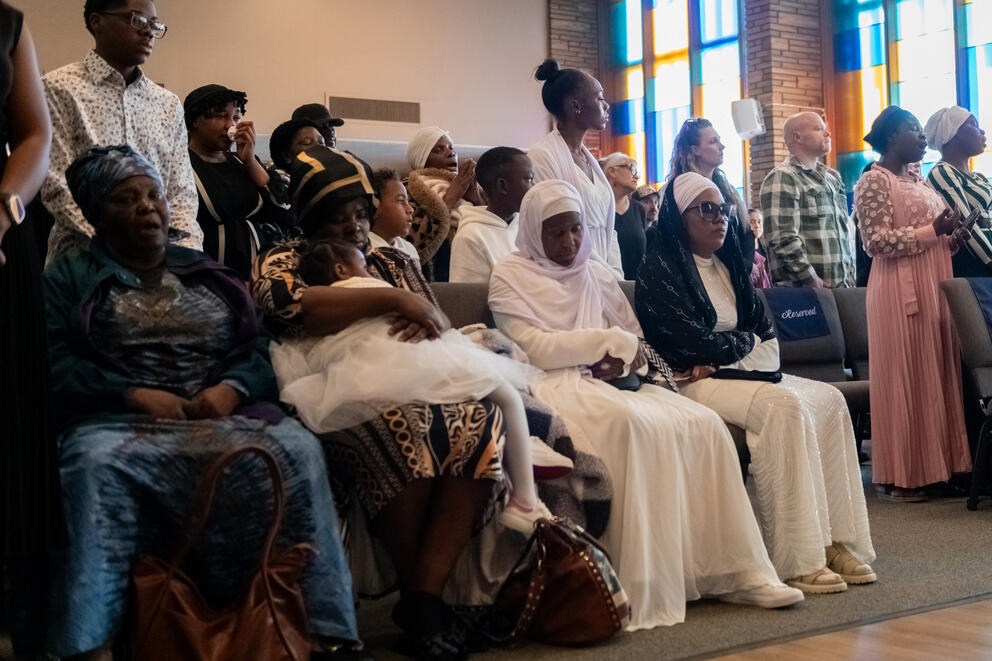 People sit and stand while paying attention to a speaker off-camera
