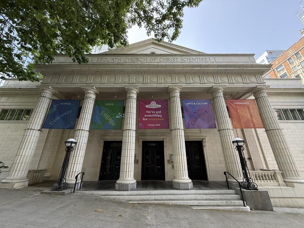 photo of a neo-classical white building with columns and colorful banners 