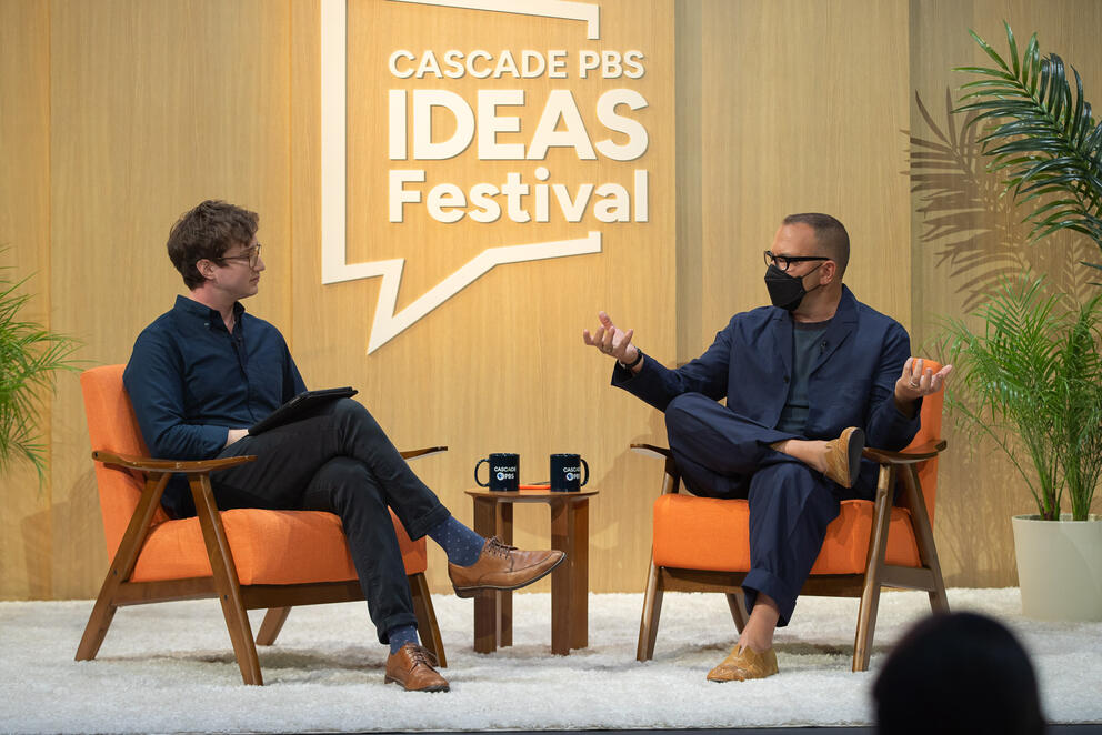 Two men sit on chairs at the Cascade PBS Ideas Festival