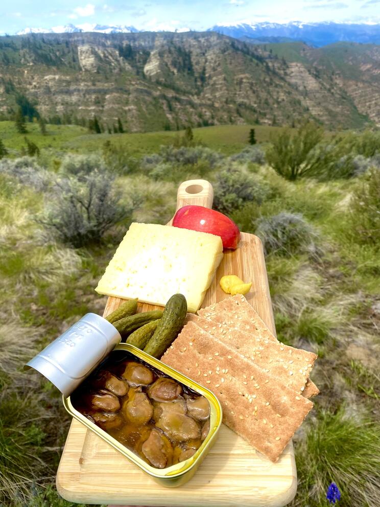 A smoked oyster charcuterie board with craggy hills in the background
