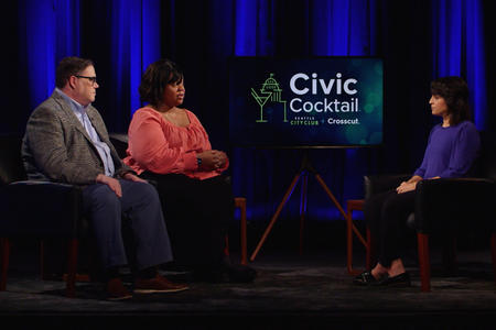 Three people sitting on a stage speaking to one another. 