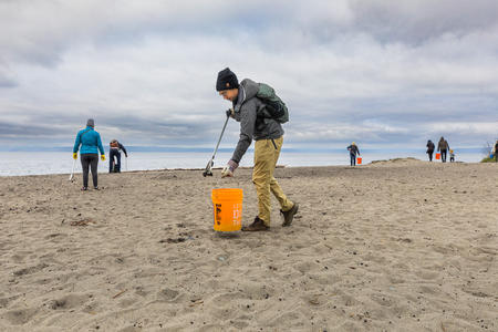 A person gathers litter on a beach