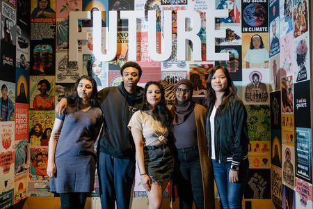 A group of kids stands in front of a wall of protest posters
