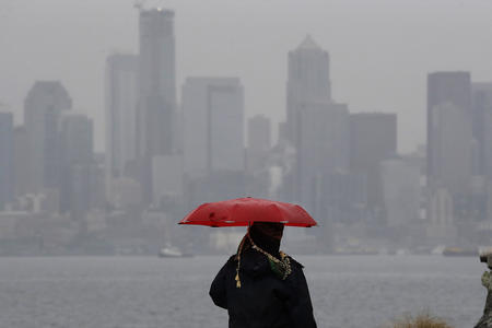 A person with an umbrella looks out to the Seattle skyline