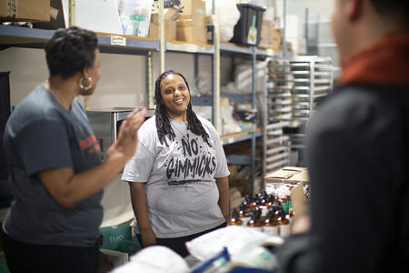 Three people talk inside a cannabis company warehouse