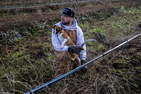 A farm worker holding a puppy in a field