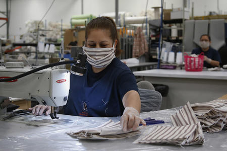 Woman with sewing machine wearing a cloth face mask 