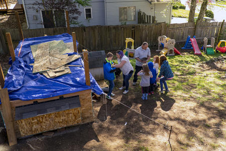 Parents show chickens to children in a backyard