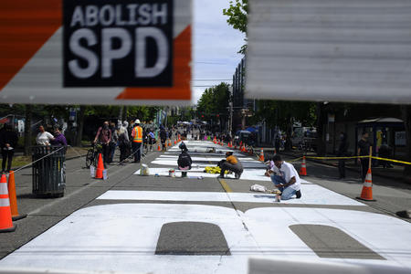 people kneeling on the ground painting a black lives matter mural