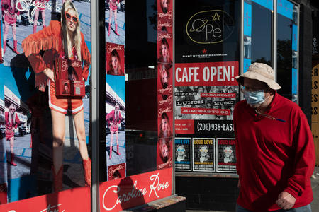 man wearing mask passes storefront