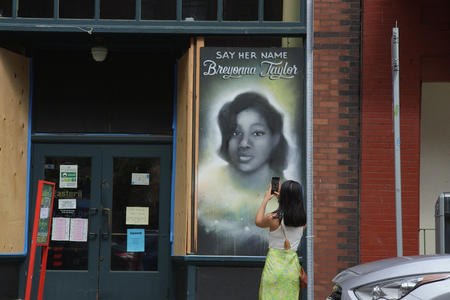 A woman takes a photo of a Breonna Taylor mural by Mari Shibuya in Seattle's International District