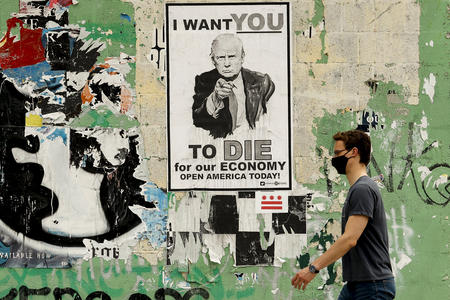 man walking past a trump poster