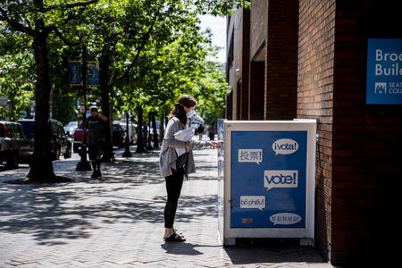 Voter drops ballot in blue drop box