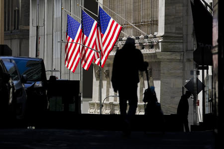 People walking on a street with two U.S. flags flying