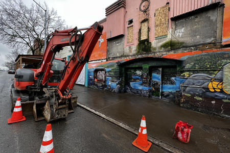 a construction digger and the battered remains of a retro pink movie theater