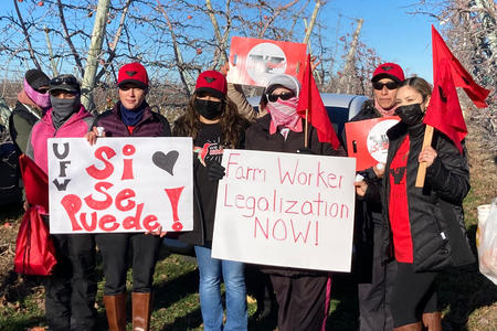 Farm workers hold vigil signs.