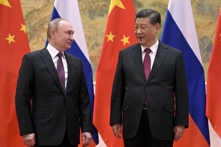 Two men in suit in front of flags