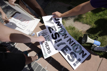 Hands reaching for placards reading “Union Yes!”