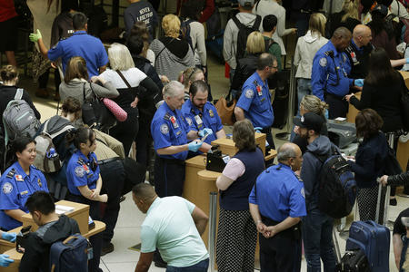 TSA agents check passenger boarding passes and identification at a security screening checkpoint, Thursday, May 19, 2016, at Seattle-Tacoma International Airport in Seattle. Airport officials announced Thursday that following a training period, several dozen contract employees will start work on Monday, May 23, 2016 to assist passengers at security checkpoints, with the goal of freeing up TSA agents and reducing passenger wait times. (AP Photo/Ted S. Warren)