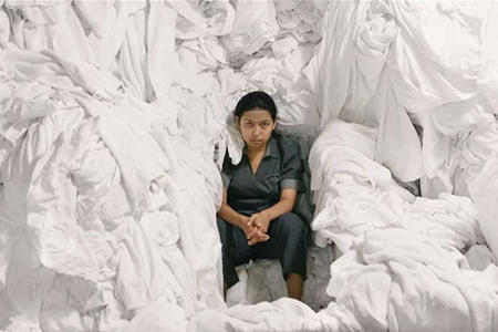 A woman sits in a pile of laundry