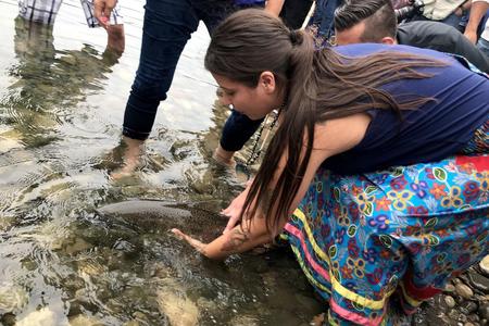 Colville Tribal member Crystal Conant releases a salmon into the upper Columbia River.