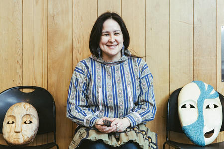 Jennifer Angaiak Wood sits with two of her masks on each side