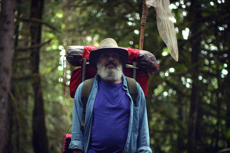bearded guy in the forest with a big backpack
