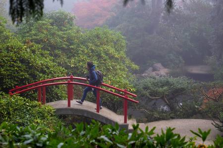 A woman walks over a bridge in the mist