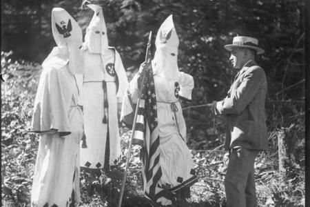Three people in white robes talking to a man in a suit