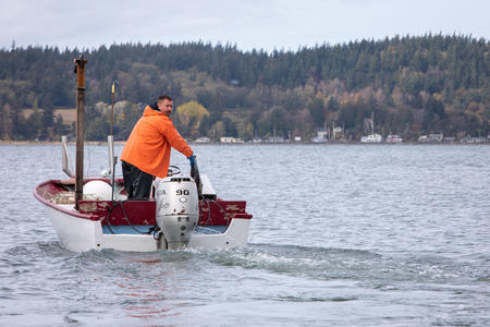 A man steers a fishing boat on the water