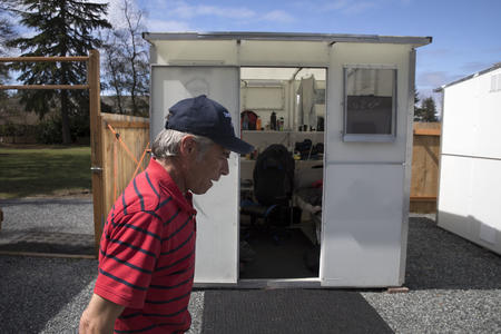 a man walks past a cabin in a tiny home village