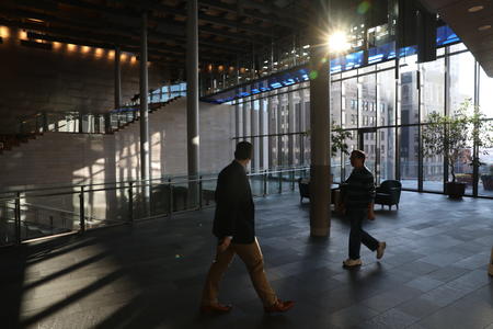 Two people walking in the lobby of city hall as shafts of sunlight stream in