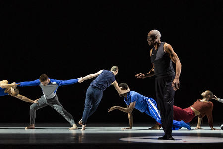 photo of a group of dancers moving on a dark stage
