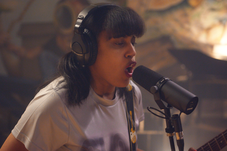 A woman with headphones singing into mic