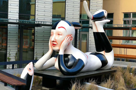 sculpture of a person with black hair and black and white outfit reclining in a fountain