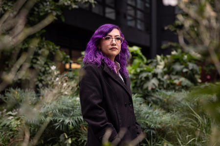 Stephanie Valerdi poses in front of lush greenery. 