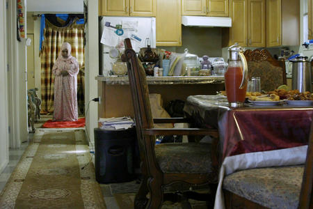 A woman praying in a kitchen doorway
