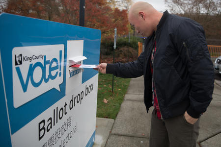 man putting ballot in ballot box